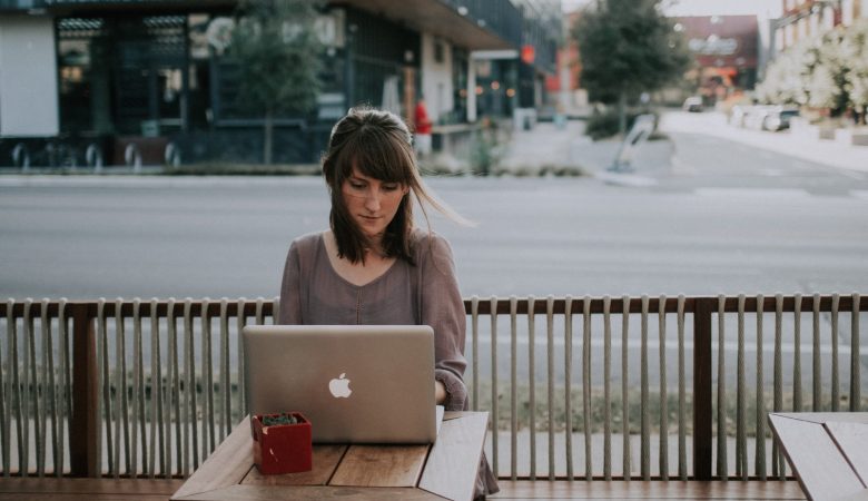 woman in gray shirt sitting on bench in front of MacBook